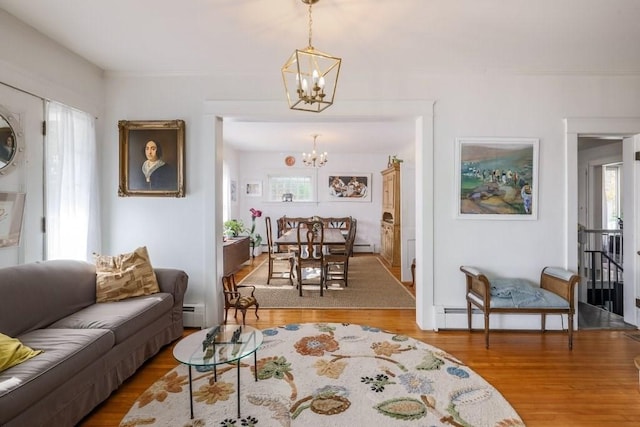 living room featuring wood-type flooring, a baseboard heating unit, and a notable chandelier