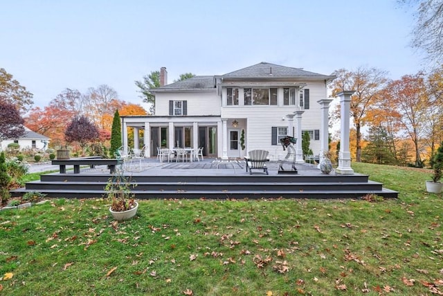 rear view of house with a wooden deck, a lawn, and a sunroom