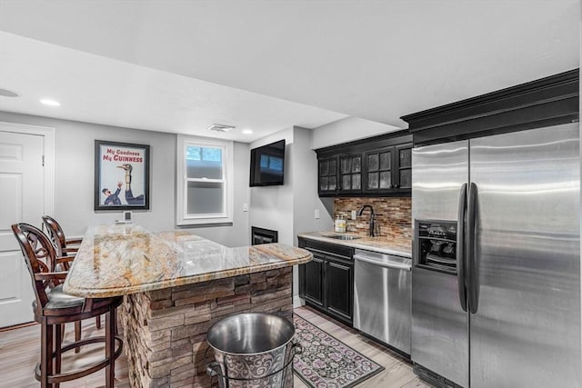 14 Glen Rd, Hopkinton, MA 01748 - kitchen featuring appliances with stainless steel finishes, light wood-type flooring, decorative backsplash, glass insert cabinets, and dark cabinetry