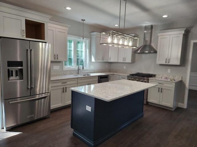 kitchen with hanging light fixtures, dark wood-type flooring, wall chimney range hood, appliances with stainless steel finishes, and a center island