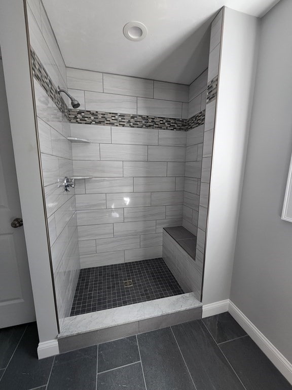 bathroom with tiled shower and tile patterned flooring