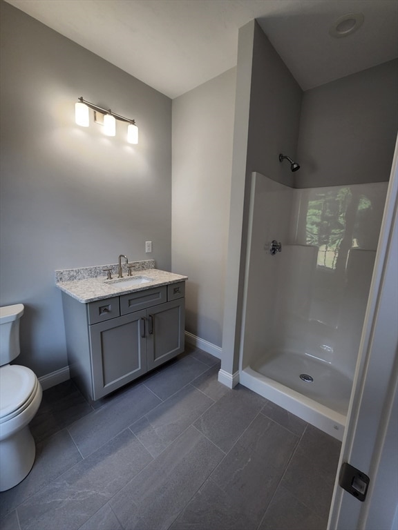 bathroom with tile patterned floors, walk in shower, vanity, and toilet