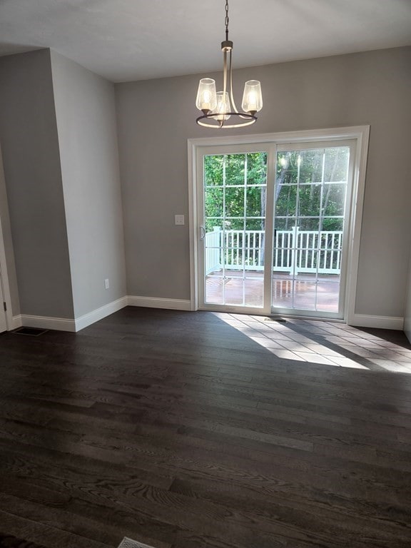 unfurnished room featuring a notable chandelier and dark hardwood / wood-style floors