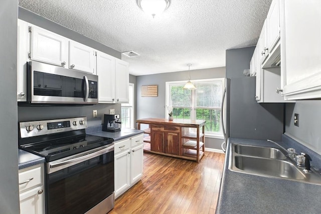 59 Castlegate Dr Unit B, Springfield, MA 01129 - kitchen featuring stainless steel appliances, white cabinets, a sink, wood finished floors, and a textured ceiling