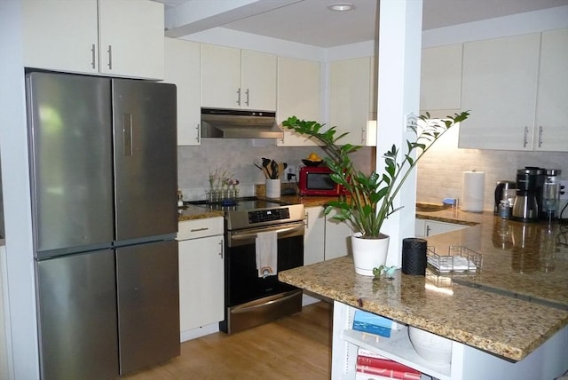 kitchen with white cabinetry, refrigerator, dark stone counters, and stainless steel electric range