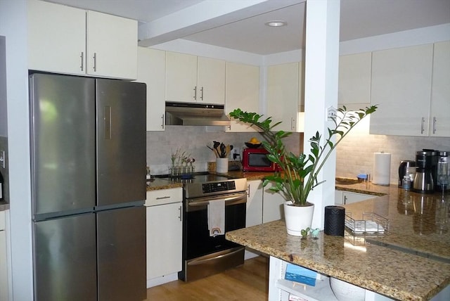 kitchen with decorative backsplash, refrigerator, dark stone counters, and stainless steel electric range