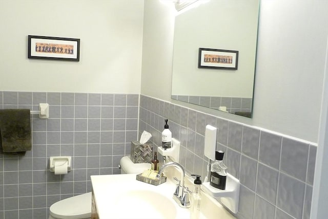 bathroom featuring vanity, tile walls, and toilet