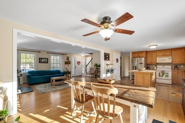 dining room with light wood finished floors, stairs, and a ceiling fan
