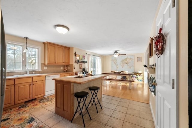 kitchen with tile counters, dishwasher, ceiling fan, a sink, and light tile patterned floors