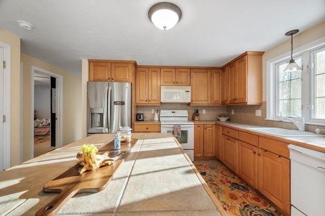kitchen featuring white appliances, tile countertops, a sink, decorative light fixtures, and backsplash