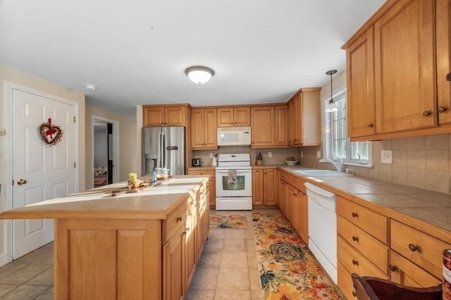 kitchen with tile counters, white appliances, tasteful backsplash, and a sink