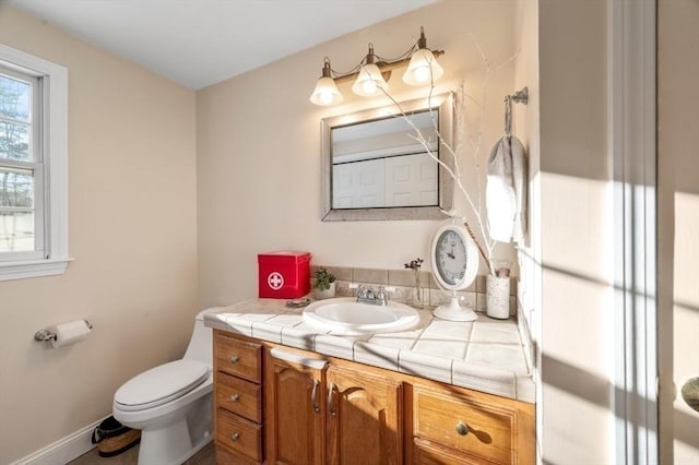 bathroom featuring toilet, vanity, and baseboards