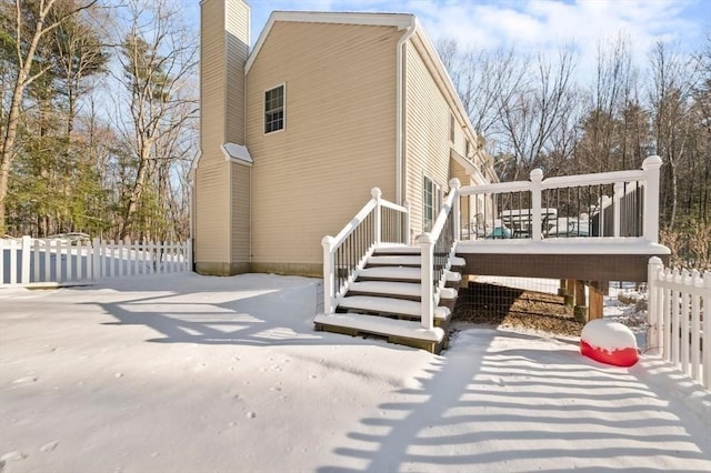view of side of home featuring a chimney, fence, a wooden deck, and stairway
