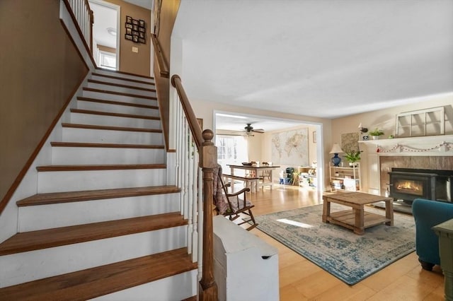 stairs with a glass covered fireplace and a ceiling fan