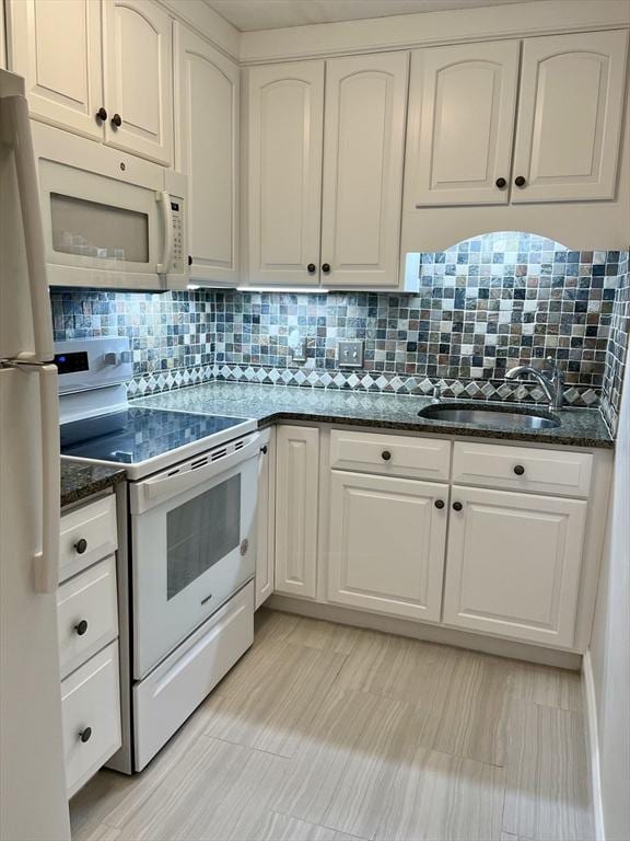 kitchen featuring dark stone countertops, backsplash, white appliances, and white cabinetry