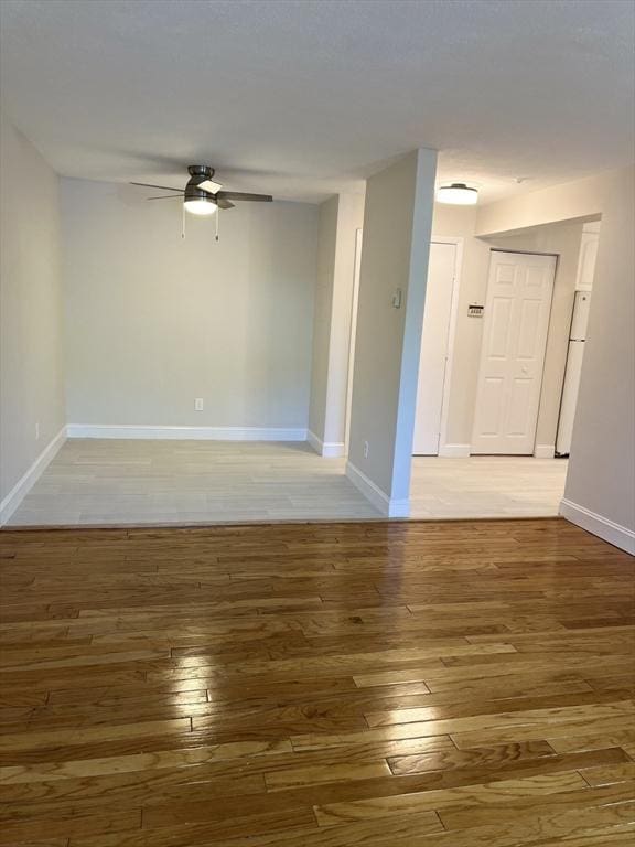 spare room with baseboards, a ceiling fan, and light wood finished floors