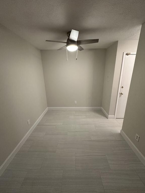 unfurnished room with baseboards, ceiling fan, and a textured ceiling