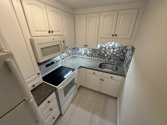 kitchen with white cabinets, a sink, white appliances, dark stone counters, and tasteful backsplash