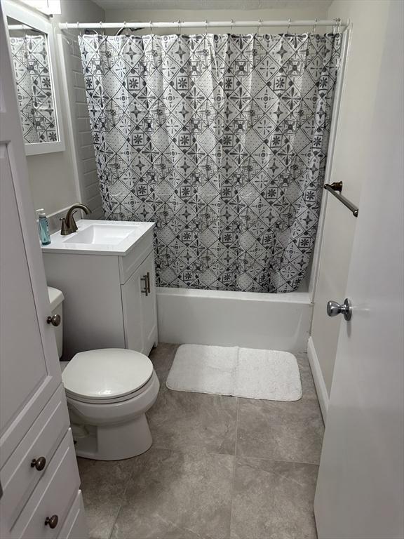 bathroom with shower / bath combo with shower curtain, tile patterned floors, toilet, and vanity