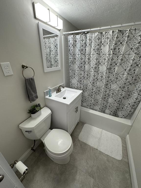bathroom featuring toilet, a textured ceiling, and vanity