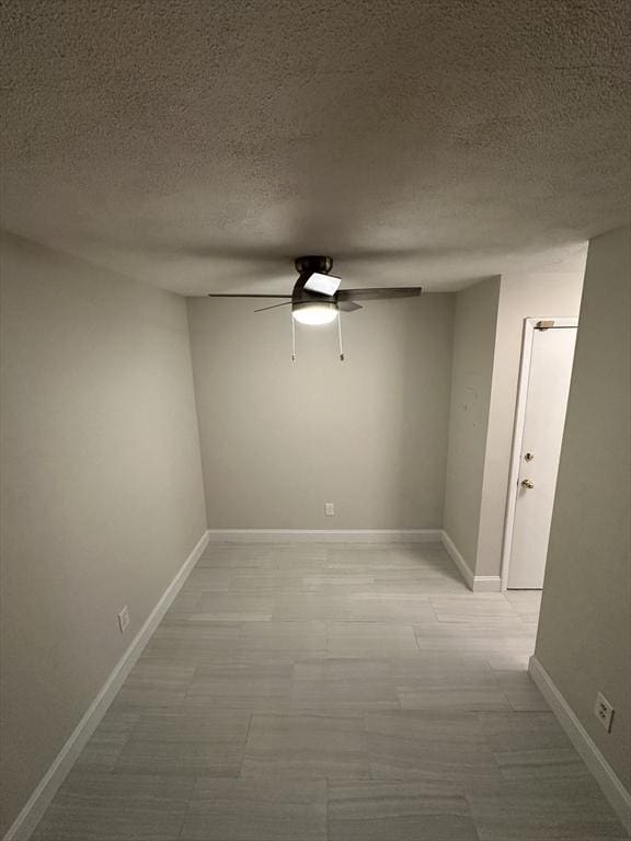 unfurnished room featuring baseboards, ceiling fan, and a textured ceiling