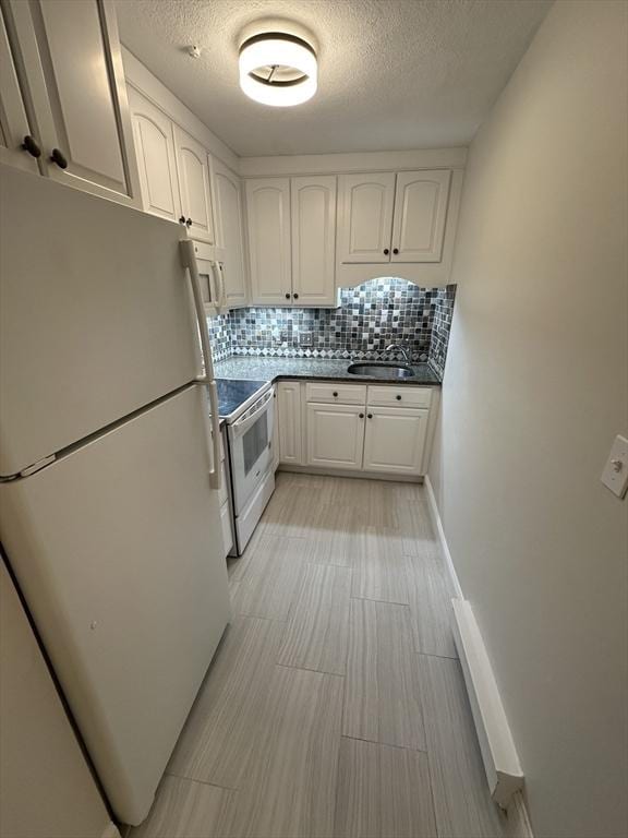 kitchen with decorative backsplash, dark countertops, a sink, white cabinets, and white appliances