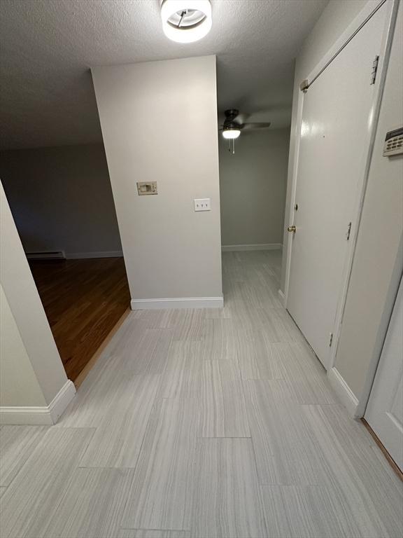 hall featuring a textured ceiling and baseboards