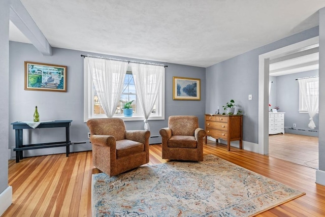 living area featuring light hardwood / wood-style flooring and a baseboard heating unit