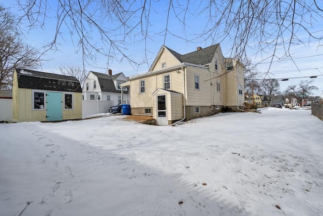 snow covered back of property with a storage shed