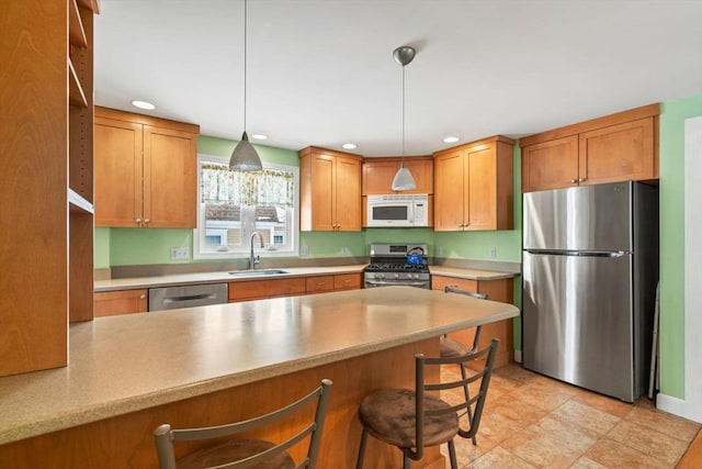 kitchen with a kitchen bar, decorative light fixtures, sink, and appliances with stainless steel finishes