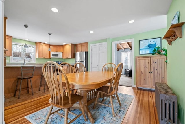 dining room with sink, radiator heating unit, and light wood-type flooring