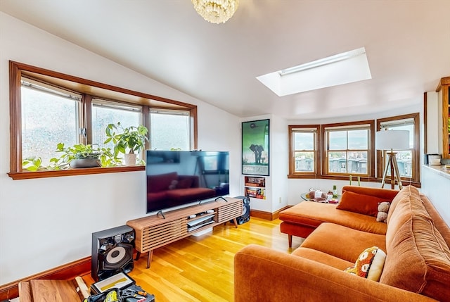 living room featuring vaulted ceiling with skylight and light hardwood / wood-style flooring