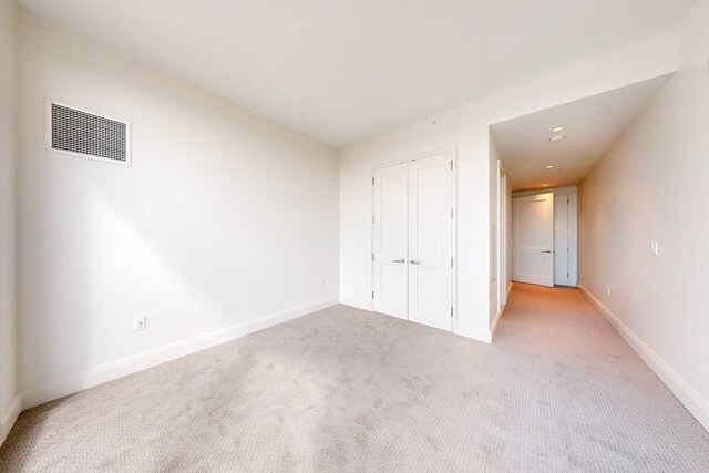 unfurnished bedroom featuring light colored carpet and a closet