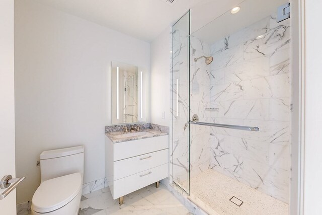 bathroom featuring a tile shower, vanity, and toilet