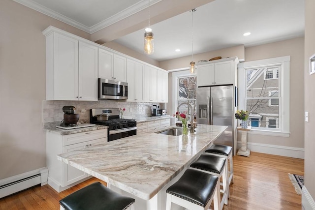 kitchen featuring sink, a breakfast bar area, a baseboard radiator, pendant lighting, and stainless steel appliances