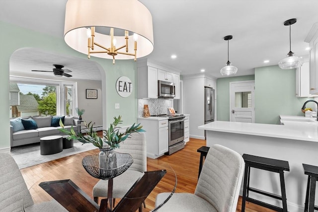 10 Highfield Ter, Boston, MA 02131 - kitchen with appliances with stainless steel finishes, arched walkways, white cabinetry, light countertops, and tasteful backsplash