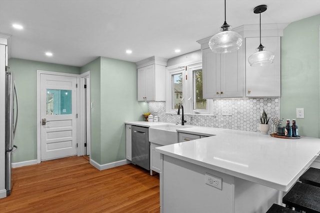 10 Highfield Ter, Boston, MA 02131 - kitchen featuring stainless steel appliances, light wood finished floors, a peninsula, a breakfast bar area, and backsplash