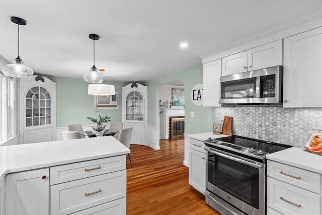 10 Highfield Ter, Boston, MA 02131 - kitchen with stainless steel appliances, light countertops, white cabinetry, backsplash, and hanging light fixtures