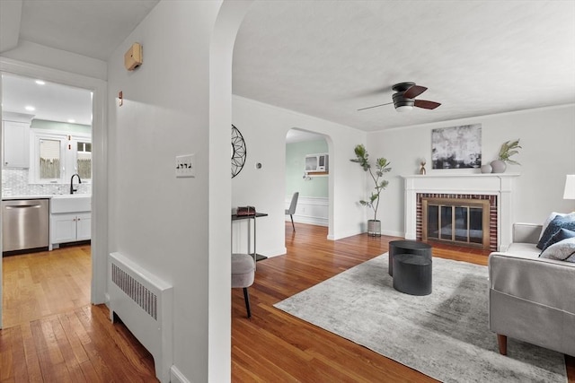 10 Highfield Ter, Boston, MA 02131 - living area featuring radiator, arched walkways, a ceiling fan, light wood-type flooring, and a fireplace