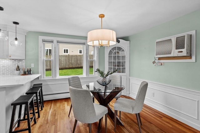 10 Highfield Ter, Boston, MA 02131 - dining area with wood finished floors, a wall unit AC, a wainscoted wall, and a baseboard heating unit