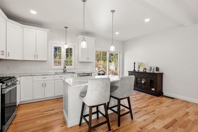 kitchen featuring a sink, range with gas stovetop, backsplash, and white cabinetry