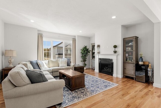 living room with a fireplace, recessed lighting, baseboards, and light wood-type flooring