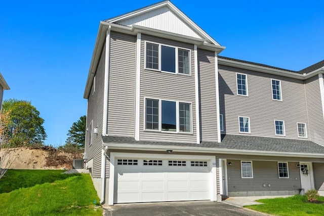 view of property with aphalt driveway, central AC unit, a front lawn, and a garage