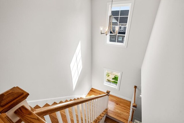 stairway featuring baseboards, a chandelier, and a towering ceiling