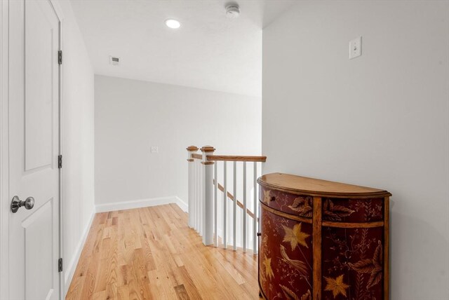 hallway with visible vents, baseboards, light wood-type flooring, recessed lighting, and an upstairs landing