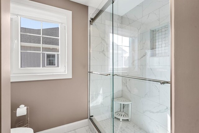bathroom featuring baseboards, marble finish floor, a stall shower, and toilet