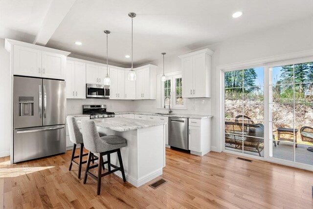 kitchen with appliances with stainless steel finishes, tasteful backsplash, a center island, and visible vents