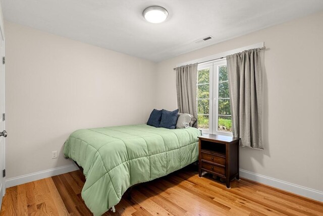 bedroom featuring baseboards, wood finished floors, and visible vents