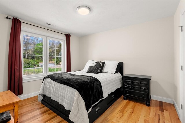 bedroom with baseboards, visible vents, and light wood finished floors