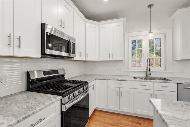 kitchen featuring white cabinets, appliances with stainless steel finishes, a sink, and tasteful backsplash